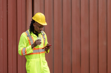 Man in hard hat drinking water at containers cargo, Worker taking a break, Warehouse dock worker using smartphone in shipping container shipping yard