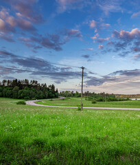 Fototapeta premium Rural landscape with a long road and a tall power pole