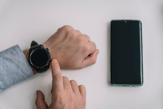 man is holding a smartphone and a smartwatch in his hand. wireless connection of the watch and mobile phone. smart phone and smart watch wi-fi connect