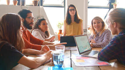 Multi-Cultural Business Team Meeting Around Table In Office With Laptop And Documents