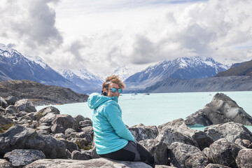 Female tourist enjoying breathtaking view of tasman lake and southern alps in new zealand