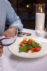 Man sitting at a table with a glass of red wine and pasta