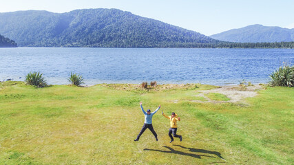 Hikers jumping by lake ianthe, south island, new zealand