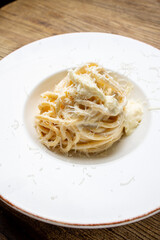 Spaghetti carbonara with parmesan cheese on a white plate