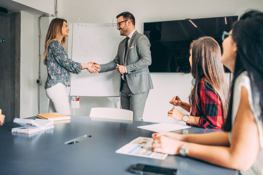 Business people shaking hands in conference room at office.