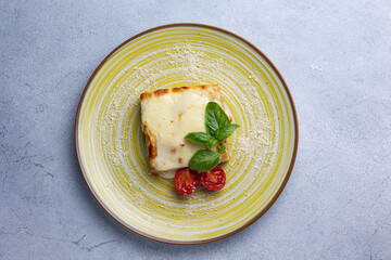 Italian lasagna on a blue plate with a fork and basil leaf
