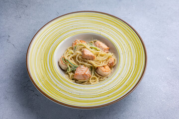 Spaghetti with salmon and herbs in a bowl on the table.
