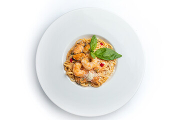 Spaghetti with shrimps and basil on a white plate.