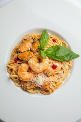 Spaghetti with shrimps and basil on a white plate.