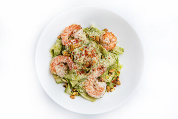 Spaghetti with shrimps and basil on a white plate.