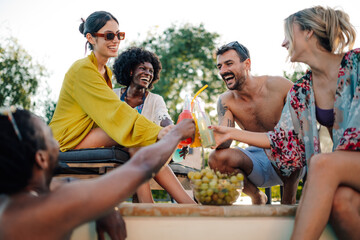 Friends toasting colorful drinks at a pool party