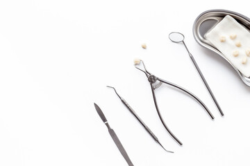 Dental crowns with steel instruments for dental prosthetics, top view. Dentist desk, white background