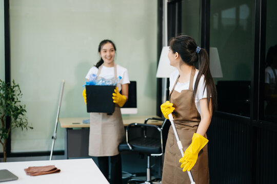 Two professional cleaners tidying a stylish space with a smile. Experience efficient and friendly house cleaning