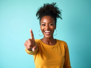 Cheerful young woman pointing finger on turquoise background