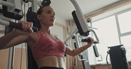 A woman focused on strength training at the gym using a weight training machine
