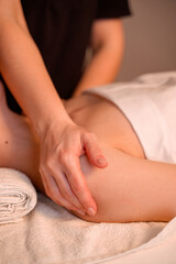 A woman lies on a massage table in a cozy spa salon while a professional masseur gently rubs her shoulders and back, creating a soothing and relaxing experience