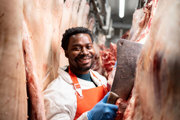 Professional butcher working with raw meat in food factory.