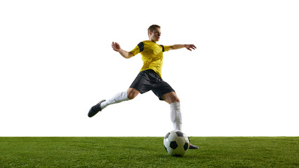 Low angle view of focused male soccer player in yellow jersey and black shorts in motion on field, kicking ball against white background. Concept of sport, action, competition, game, active lifestyle