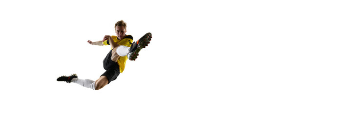 Dynamic image of man, soccer player during intensive match, kicking ball mid-air, playing isolated...