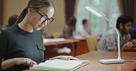 A Focused Student Absorbed in Their Study at a WellLit and Organized Table Setting