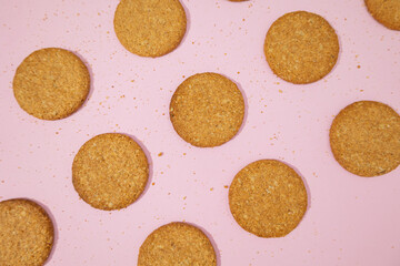 Top view of whole grain oatmeal cookies scattered on a pastel pink background, cookies made from...