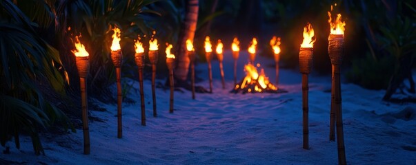 Tiki torches lighting a sandy pathway to a bonfire on a tropical beach at night