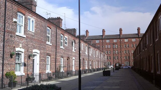 Wide shot panning back and forth on Anita Street in Ancoats, Manchester, showcasing historic red brick terraced houses with a public walkway in a classic northern England setting.