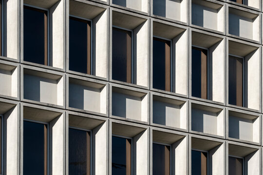 Symmetrical concrete grid of a brutalist-style building with repetitive windows.