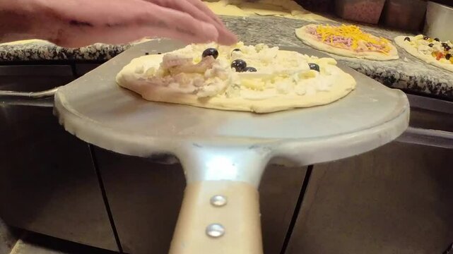 Pr&eacute;paration de la pizza au fromage sur la pelle &agrave; pizza et insertion dans le four au feu de bois | mode POV