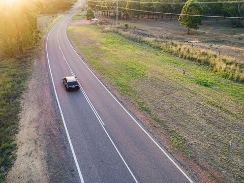 Car traveling down country road at sunset