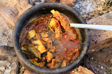 Authentic mutton curry making on indian rural areas non veg dish cooking with clay pot process on Rural kitchen using bio wood fuel for traditional stoves. hot red gravy in countryside of india