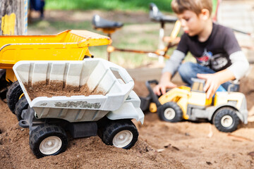 Boy playing in sandpit with toy trucks