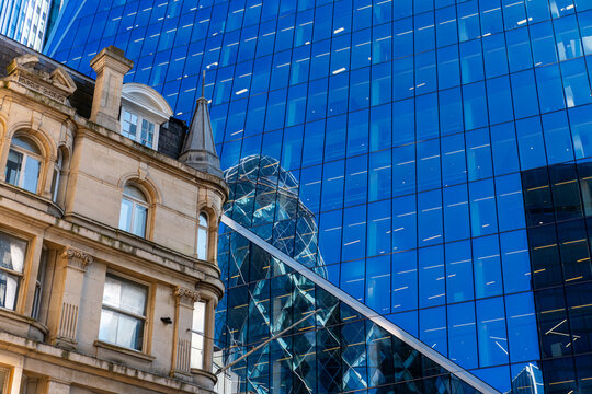 Historical and modern architecture reflected on a blue glass facade in the city.