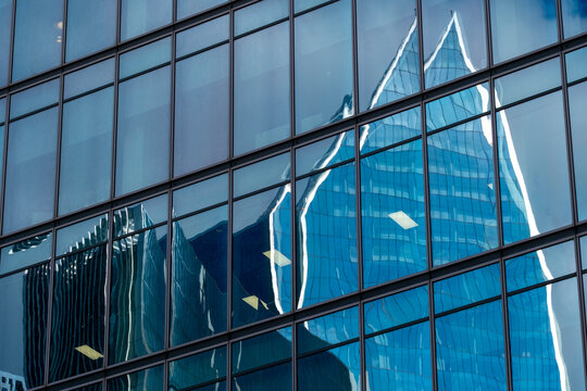Close-up of a modern glass facade reflecting angular skyscraper designs.