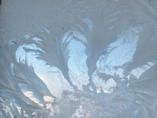 This stunning image features a closeup of intricate frost on a window, beautifully contrasting...