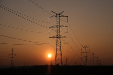 Fototapeta premium Power poles against the sky with the setting sun.