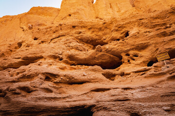 Eroded canyon wall with many holes. Layered rock texture.