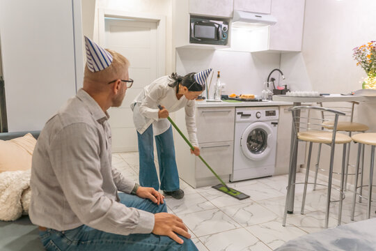 Couple Cleaning Apartment Birthday; Post-party cleanup; man woman mopping floor; modern kitchen setting.