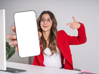 Pointing phone mock up, portrait of young caucasian brunette business woman sit office desk holding pointing phone mock up empty blank white screen. Online mobile offer advertisement concept idea.