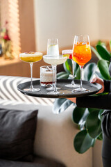 A person holds a black tray featuring an array of colorful cocktails, showcasing a vibrant...