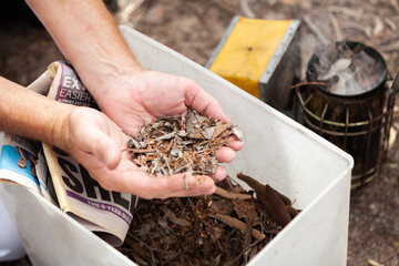 Hands holding tinder for using in bee smoker