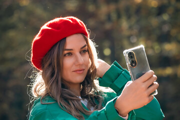Woman Selfie Phone Autumn Park - Young woman takes a selfie with her smartphone while enjoying the fall scenery in a park.