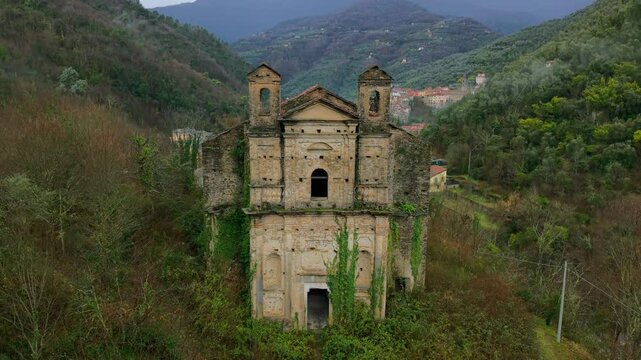 Crumbling facade of Chiesa San Michele Arcangelo, a testament to time and decay, set against a serene valley backdrop.aerial rising shot
