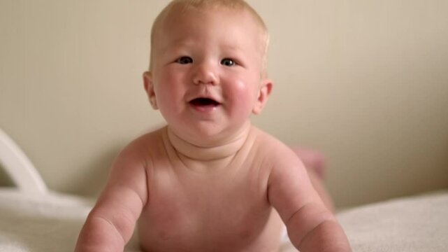 smiling infant baby lies on their tummy, looking up with bright eyes, Cild face expresses pure joy and curiosity, baby emotions, childhood happiness, home comfort