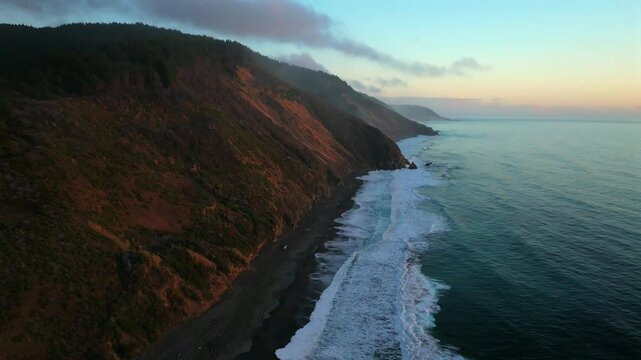 Northern California waves crashing bluffs cliffside mountain rocky rugged remote coastline aerial drone USAL Beach Campground sunset Sinkyone Wilderness surf swell black sand circle left down