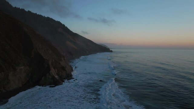 Northern California waves crashing bluffs cliffside mountain rocky rugged remote coastline aerial drone USAL Beach Campground sunset Sinkyone Wilderness surf swell black sand forward motion