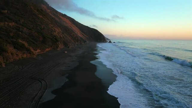 Northern California waves crashing bluffs cliffside mountain rocky rugged remote coastline aerial drone USAL Beach Campground sunset Sinkyone Wilderness surf swell black sand 4wd tracks forward motion