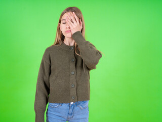 Tired overworked beautiful teen girl wearing green sweater has sleepy expression, gloomy look,...