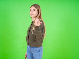 beautiful teen girl wearing green sweater inviting to come with hand. Happy that you came
