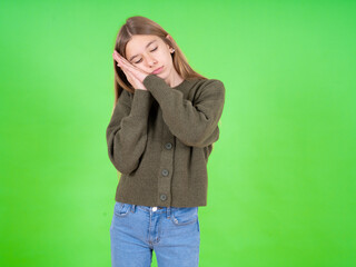 beautiful teen girl wearing green sweater sleeping tired dreaming and posing with hands together while smiling with closed eyes.